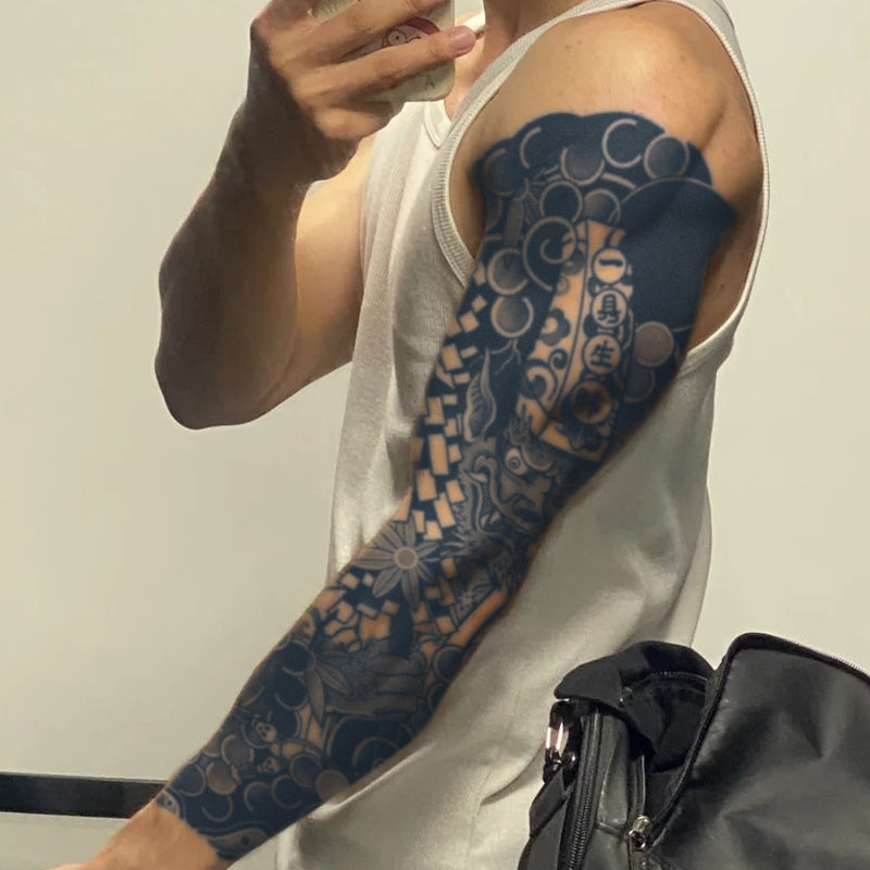 Person with a detailed tattoo on their arm, wearing a white tank top, taking a mirror selfie.
