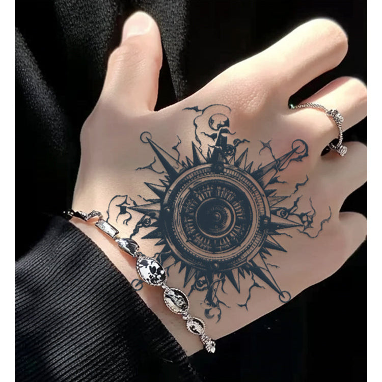 Hand with intricate tattoo and jewelry against a black background