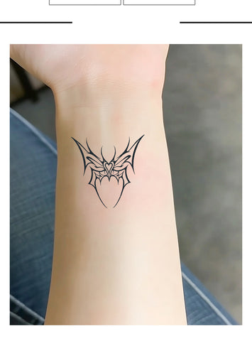 Black tattoo of a spider web on a person's wrist with a blurred background